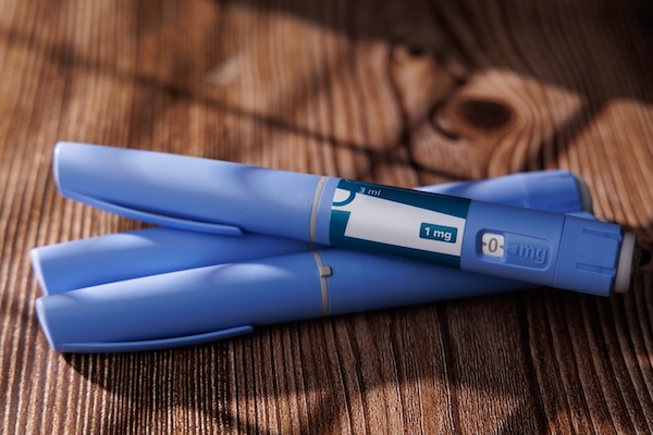 Semaglutide GLP-1 injector pens on a dark wood surface